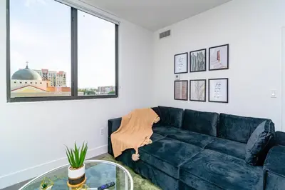 a living room with a blue couch and a glass table at Stylish 2BR Miami Retreat Mins to Wynwood and Brickell in Miami