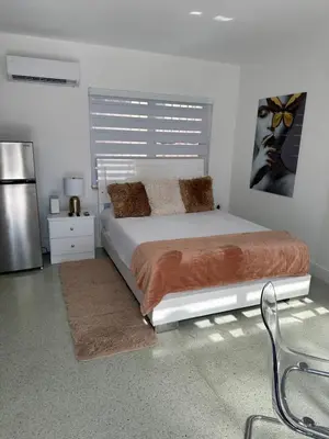 a white bedroom with a bed and a refrigerator at Villa Clara VIP-Little Havana in Miami