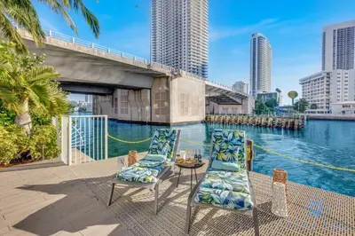 a patio with chairs and a table next to a body of water at Modern Resort with Amazing Pool in Hallandale Beach