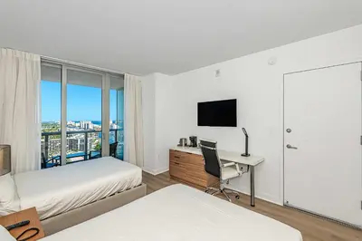 a bedroom with two beds and a desk with a computer at Lovely Studio with Amazing Views in Hallandale Beach