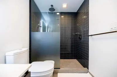 a bathroom with a toilet and a shower with black tiles at Charming 2 BR Downtown Miami 2106 Free Parking in Miami