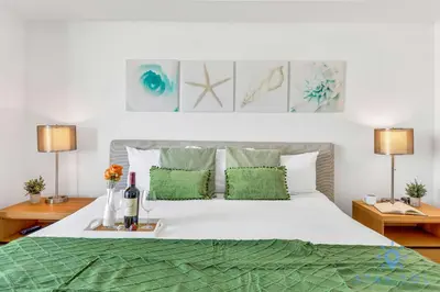 a bedroom with a white bed with green pillows at Amazing Apartment with Balcony & Pool in Hallandale Beach