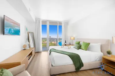 a white bedroom with a large bed and a window at Urban Apartment Balcony & Pool in Hallandale Beach