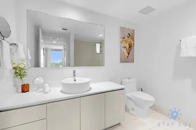 a white bathroom with a sink and a toilet at 1 BR Modern Resort Balcony Gym & Amazing Pool in Hallandale Beach