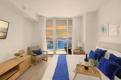 a bedroom with a blue bed and a view of the ocean at 1 BR Apartment Modern Resort Balcony & Gym in Hallandale Beach