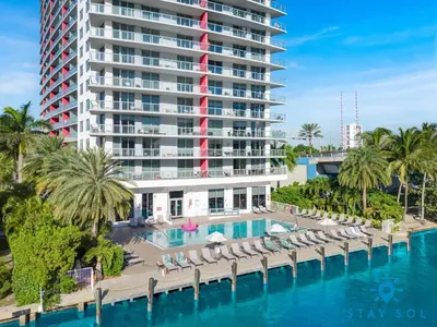 a hotel with a pool and chairs and a building at 1 BR Apartment Modern Resort Balcony & Gym in Hallandale Beach