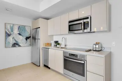 a kitchen with white cabinets and stainless steel appliances at 1 BR Apartment Modern Resort Balcony & Gym in Hallandale Beach