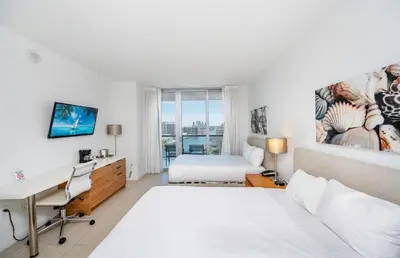 a white bedroom with a desk and a bed at 2 Bed & 2 Bath at Beachwalk With Pool Gym on 16fl in Hallandale Beach