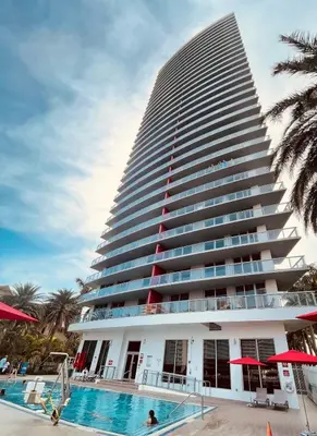 a tall building with a swimming pool in front of it at 1 Bed & Kitchen at Beachwalk With Pool Gym Beach in Hallandale Beach