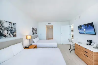 a hotel room with a bed and a desk with a computer at Amazing Family Studio at Beachwalk on Hallandale in Hallandale Beach