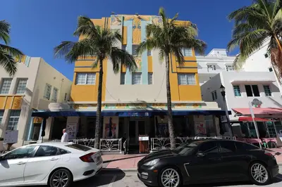 two cars parked in front of a building with palm trees at Art Deco Suite Steps from Beach in South of Fifth in Miami Beach