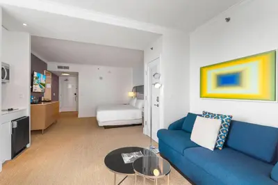 a living room with a blue couch and a bedroom at Fontainebleau Hotel Junior Suite in Miami Beach