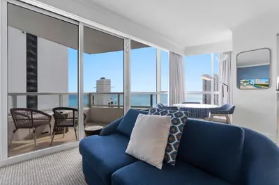 a living room with a blue couch and views of the ocean at Fontainebleau Hotel One Bedroom Suite in Miami Beach