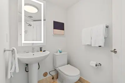 a white bathroom with a toilet and a sink at Fontainebleau Hotel One Bedroom Suite in Miami Beach