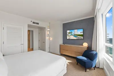 a bedroom with a bed and a blue chair at Fontainebleau Hotel One Bedroom Suite in Miami Beach
