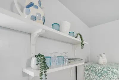 a white shelf with blue glasses and vases on it at Cozy Casarita Cottage in Miami