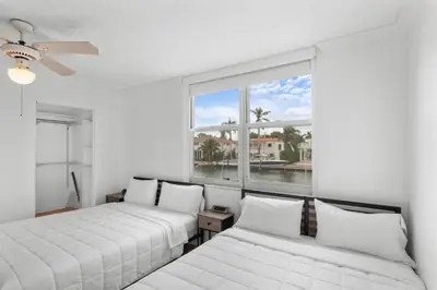 two beds in a room with a large window at Bay Harbor Sunset Apt 2C in Miami Beach