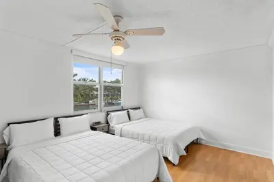 two beds in a room with a ceiling fan at Bay Harbor Sunset Apt 2C in Miami Beach