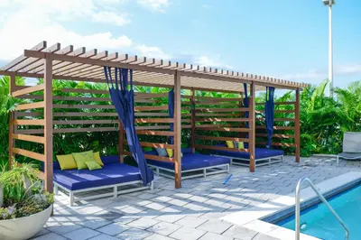 a pergola over a swimming pool with blue cushioned chairs and a blue at Stylish and Spacious Condo Prefect to Enjoy Miami! in Miami