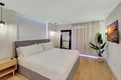 a bedroom with a large white bed and a potted plant at Modern 2Bedroom in South Beach - Steps away from Lincoln Rd in Miami Beach
