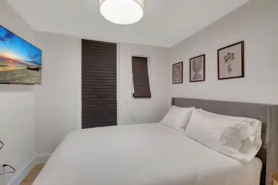 a bedroom with a white bed and a tv at Modern 2Bedroom in South Beach - Steps away from Lincoln Rd in Miami Beach