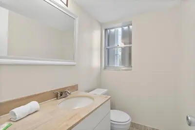 a bathroom with a sink and a mirror and a toilet at Bay Harbor Sunset Apt 3C in Miami Beach