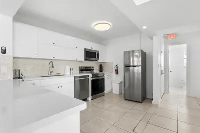 a kitchen with white cabinets and stainless steel appliances at Bay Harbor Sunset Apt 4A in Miami Beach