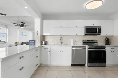 a kitchen with white cabinets and a black appliance at Bay Harbor Sunset Apt 4A in Miami Beach