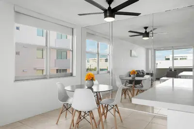 a dining room with white tables and chairs and windows at Bay Harbor Sunset Apt 4A in Miami Beach