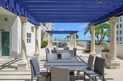 a patio with tables and chairs with the ocean in the background at Stylish Brickell Condo with Stunning Views & Premier Amenities in Miami