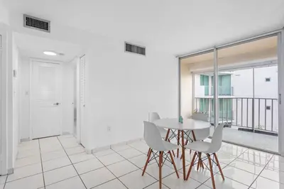 a dining room with a table and white chairs at Bay Harbor Sunset Apt 4B in Miami Beach