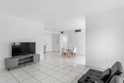 a living room with a tv and a couch and chairs at Bay Harbor Sunset Apt 4B in Miami Beach
