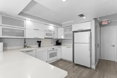 a kitchen with white cabinets and a white refrigerator at Bay Harbor Sunset Apt 5A in Miami Beach