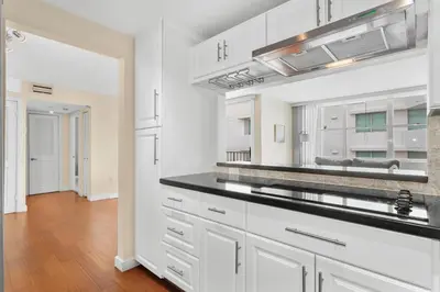 a kitchen with white cabinets and a black counter top at Bay Harbor Sunset Apt 5B in Miami Beach
