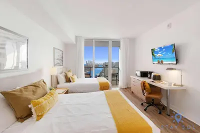 a hotel room with a bed and a desk and a deskablish at Stylish Apartment Pool & Balcony in Hallandale Beach