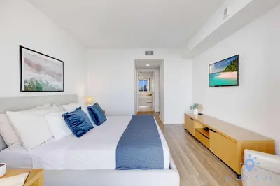 a bedroom with a large bed with blue pillows at Stylish Beach Apartment with Pool in Hallandale Beach