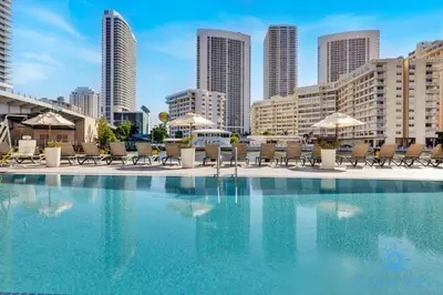 a swimming pool with chairs and umbrellas in a city at Spectacular Apartment with Balcony & Pool in Hallandale Beach