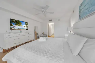 a white bedroom with a white bed and a flat screen tv at Cozy 1 Bedroom Apt in The Heart of Brickell in Miami