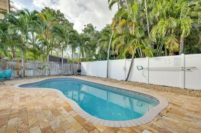 a swimming pool in a yard with a fence and trees at Shared Pool and Backyard Small and Cozy Guest House in Fort Lauderdale