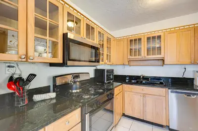 a kitchen with wooden cabinets and a stove top oven at House with Shared Pool Access 4 Mi to Beaches! in Fort Lauderdale