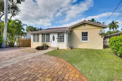 a small yellow house with a brick driveway at House with Shared Pool Access 4 Mi to Beaches! in Fort Lauderdale