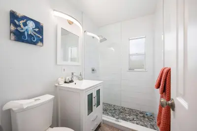 a white bathroom with a toilet and a sink at Turtle Nest Bungalow in Fort Lauderdale