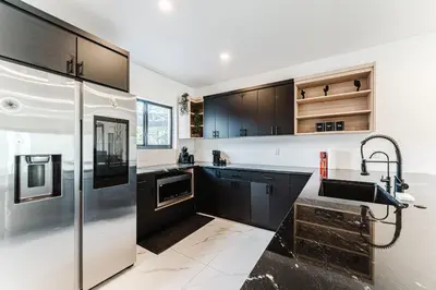a kitchen with black cabinets and a stainless steel refrigerator at Prime Location 4BR Villa with Pool in Miami