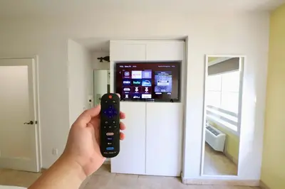 a person holding a remote control in front of a tv at Art Deco 1 Bedroom Apartment Steps to Beach in South of Fifth Neighborhood in Miami Beach