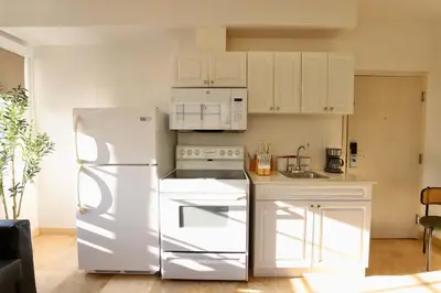 a kitchen with a white refrigerator and white cabinets at Art Deco 1 Bedroom Apartment Steps to Beach in South of Fifth Neighborhood in Miami Beach