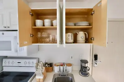 a kitchen with a sink and a stove and cabinets at Art Deco 1 Bedroom Apartment Steps to Beach in South of Fifth Neighborhood in Miami Beach