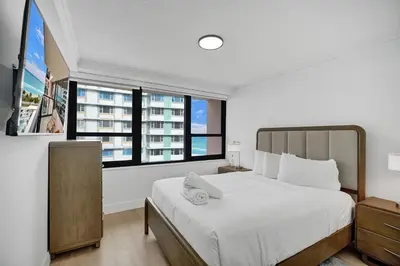 a bedroom with a large white bed and windows at Chic 2-Bedroom Condo with Beach Service & Gym / 1210 in Miami Beach