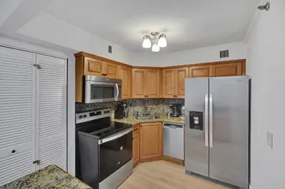 a kitchen with wooden cabinets and stainless steel appliances at Chic 2-Bedroom Condo with Beach Service & Gym / 1210 in Miami Beach