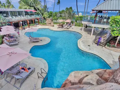a swimming pool with chairs and umbrellas at a resort at Stunning 2-Bedroom Condo with Beach Service 614 in Miami Beach