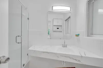 a white bathroom with a sink and a mirror at POOL & BBQ with the family in Biscayne Park